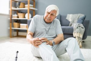 Older adult holding their knee after a fall at home, representing slip and fall injuries in Charleston.