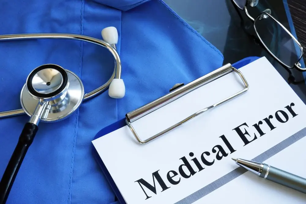 A medical error report is placed alongside a stethoscope and a doctor's robe.