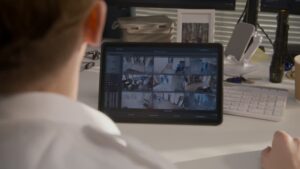 Security officer monitors CCTV cameras in coworking office on digital tablet computer. 