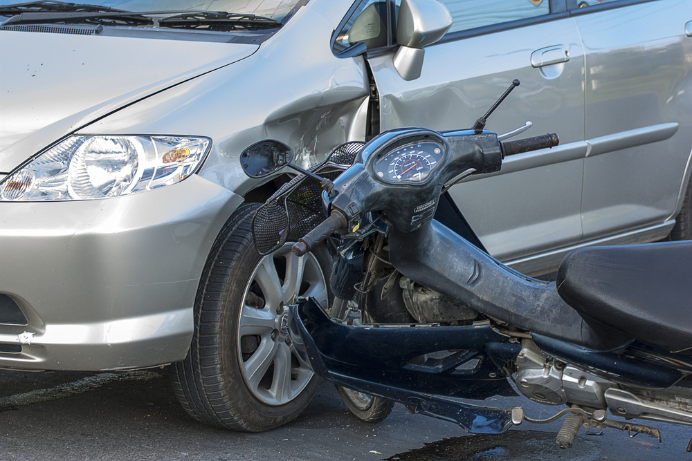 A motorcycle and silver car with visible damage after a collision at an intersection in Charleston.
