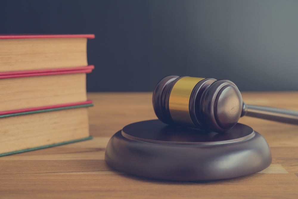 A judge’s gavel placed beside stacked law books on a wooden desk.