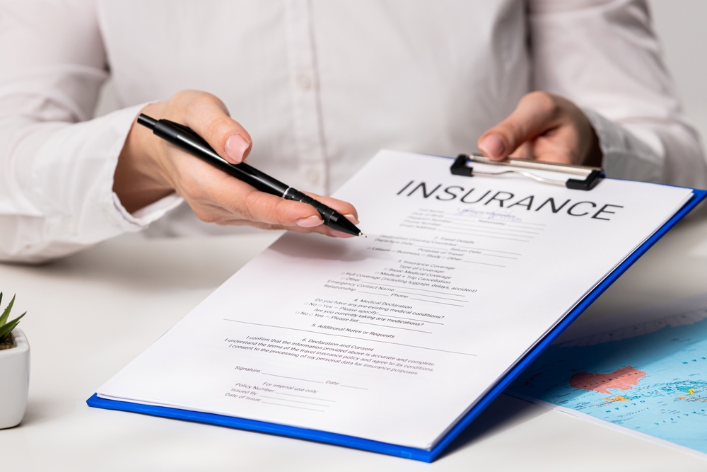 A person pointing at an insurance form with a pen.