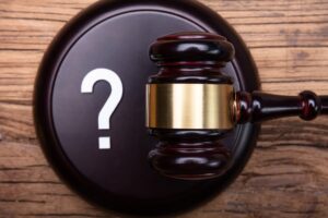 Top View Of Question Mark Sign With Gavel Over Wooden Texture Background