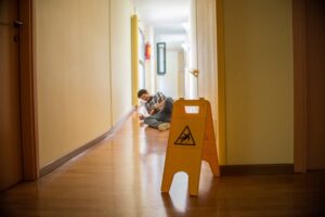 Man slips on wet floor. Wet floor danger sign in the foreground. 