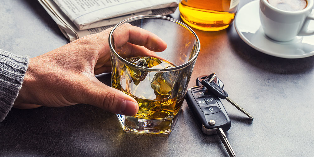 Hand holding car keys beside a glass of alcohol, representing DUI-related evidence that may support liability and Dram Shop claims in South Carolina.