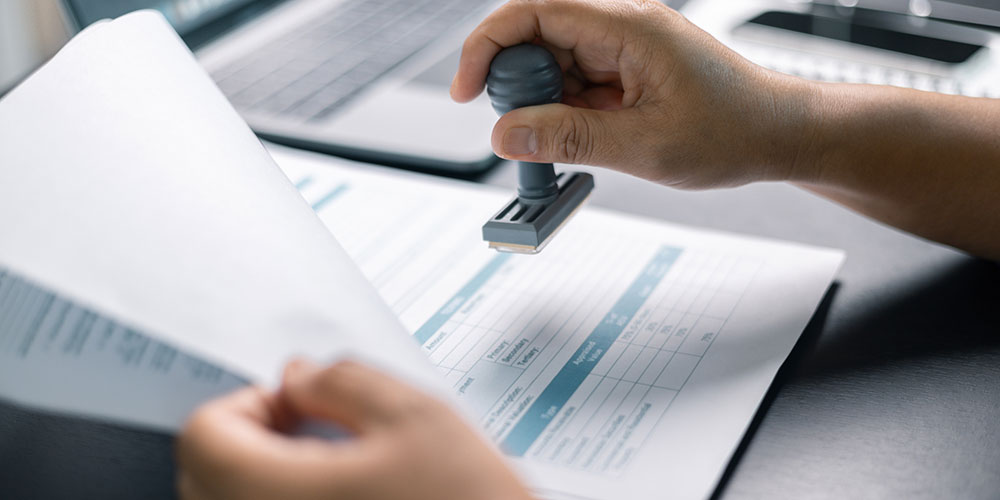 Stamped approval on a formal document, representing signing settlement paperwork and releases that can end your claim before all coverage layers are investigated.