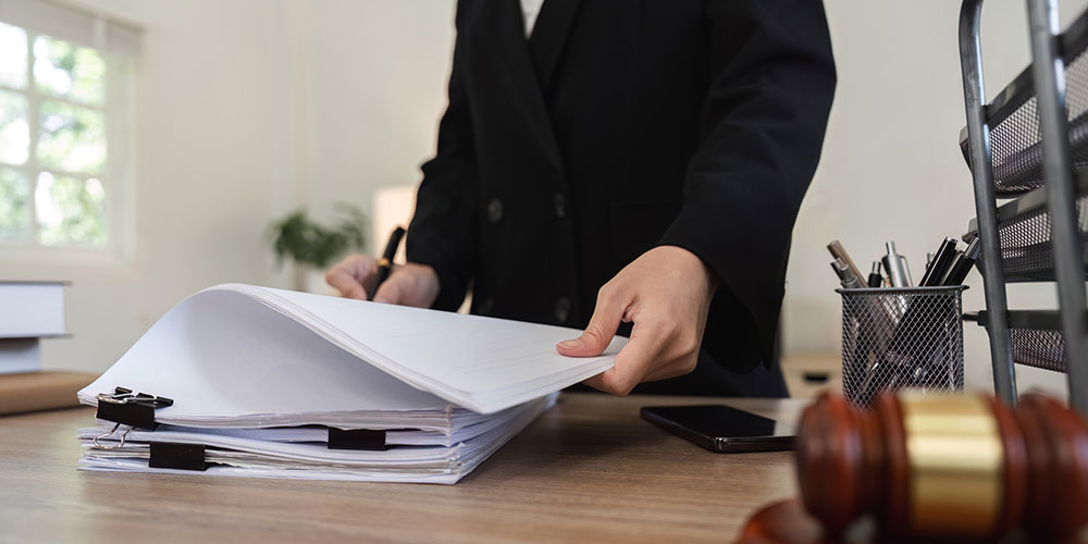 Attorney reviewing and signing consultation paperwork with a client in an office, representing what to ask before hiring a car accident lawyer.