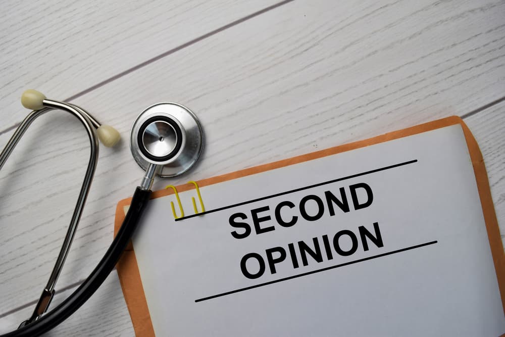 Second Opinion text with document brown envelope and stethoscope isolated on office desk.