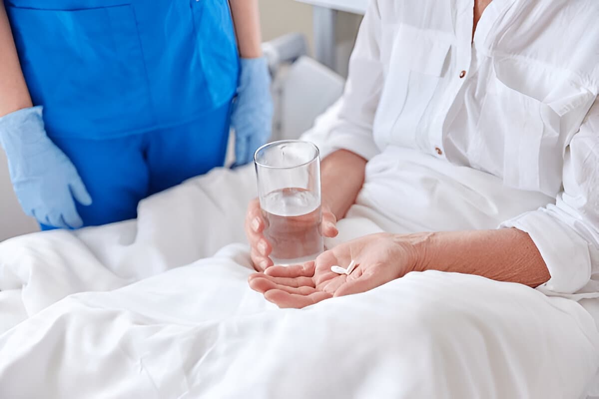Nurse giving medication and water to elderly patient